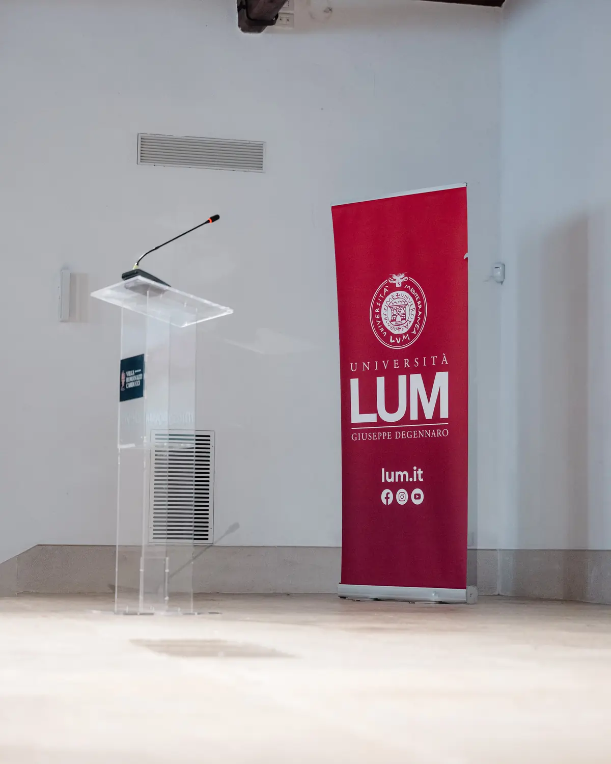 An empty lectern next to a Università LUM banner, before a session.