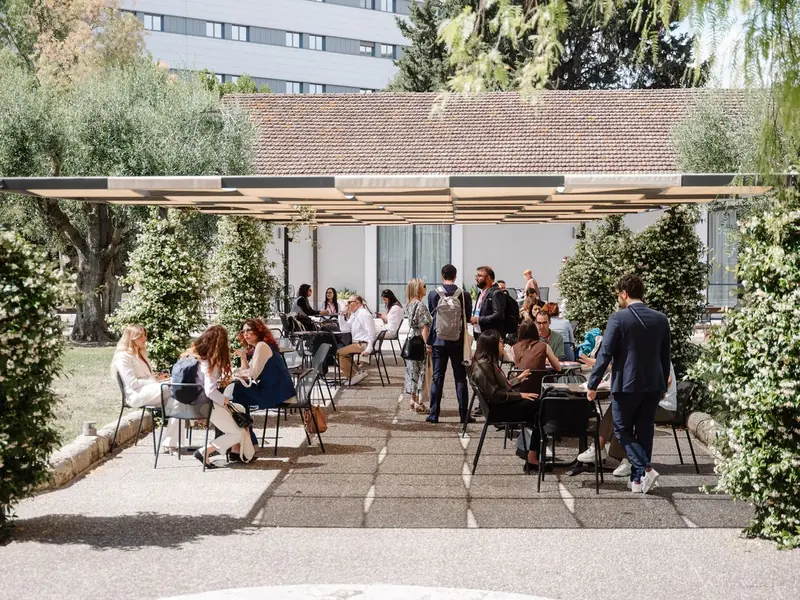 Participants at tables on a shaded terrace in the grounds of Villa Romanazzi Carducci.
